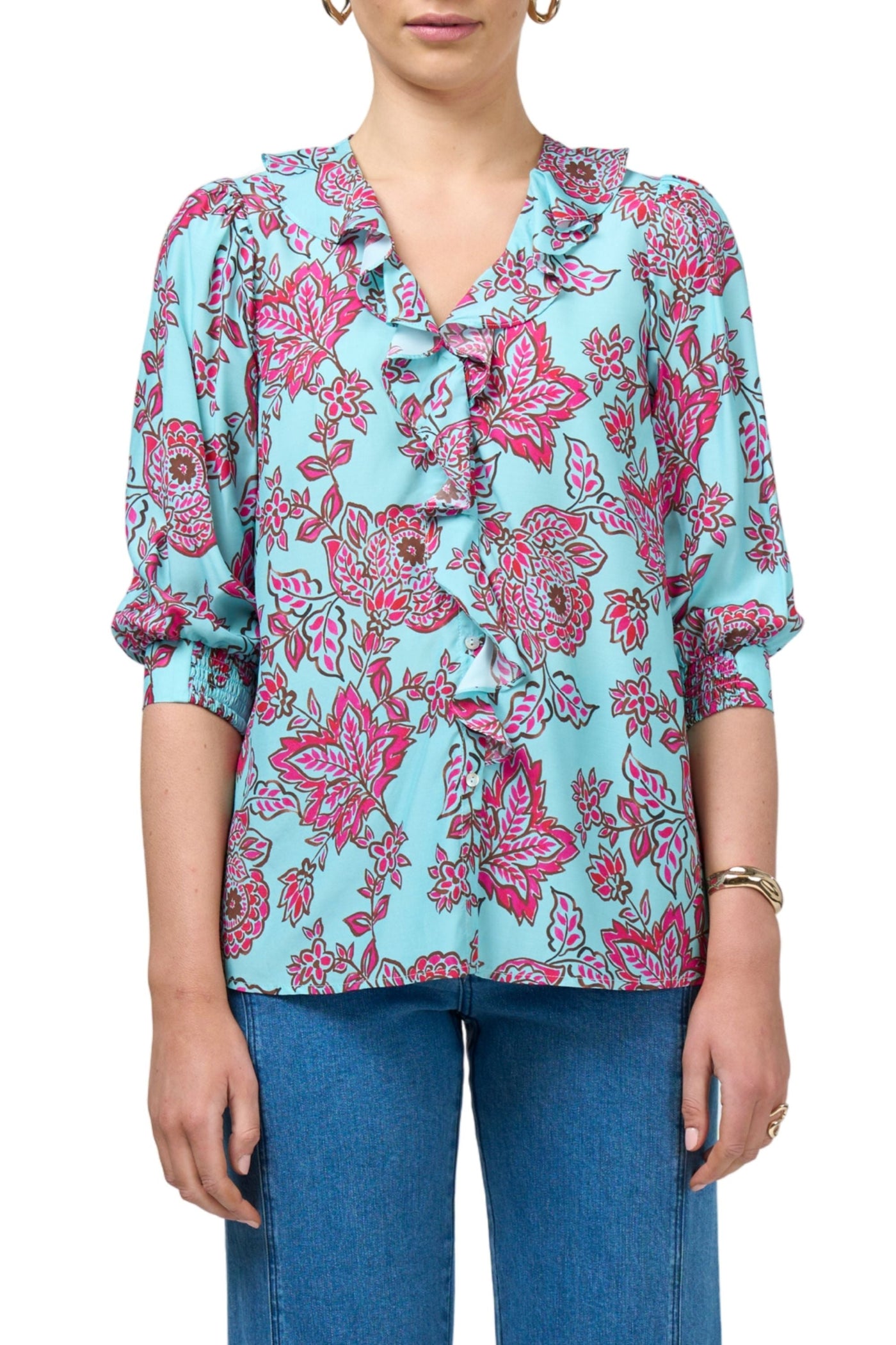 Woman wearing a blue floral blouse with pink patterns on a white background