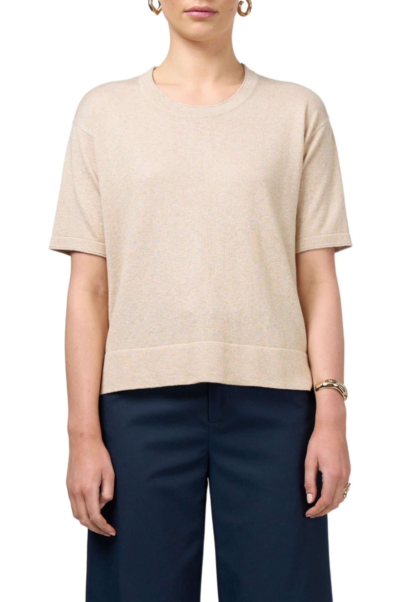Person wearing a beige sweater and navy pants on a white background