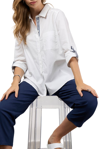 Woman wearing a white shirt and blue pants sitting on a stool against a white background