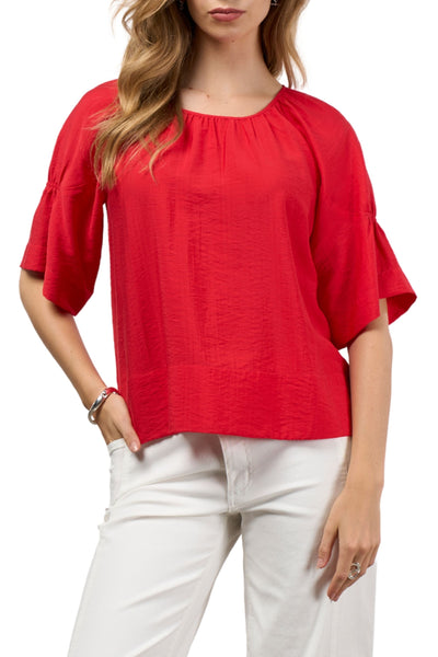 Woman wearing a red blouse and white pants on a white background