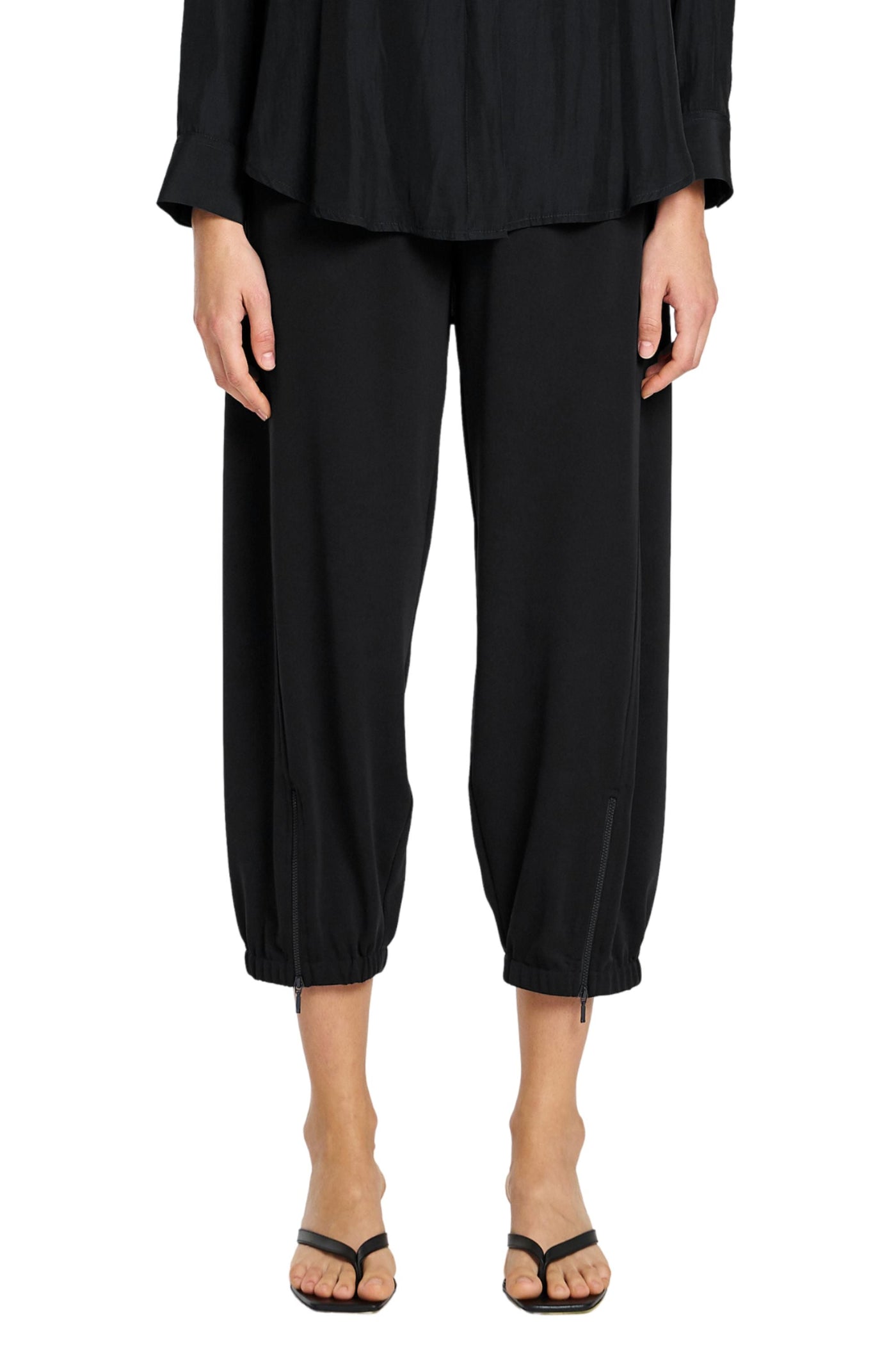 Person wearing a black outfit with wide-leg pants on a white background