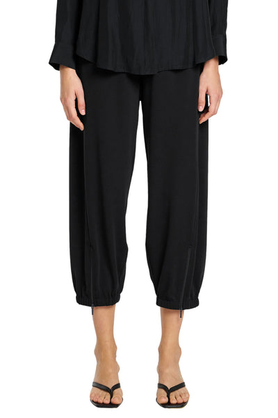 Person wearing a black outfit with wide-leg pants on a white background