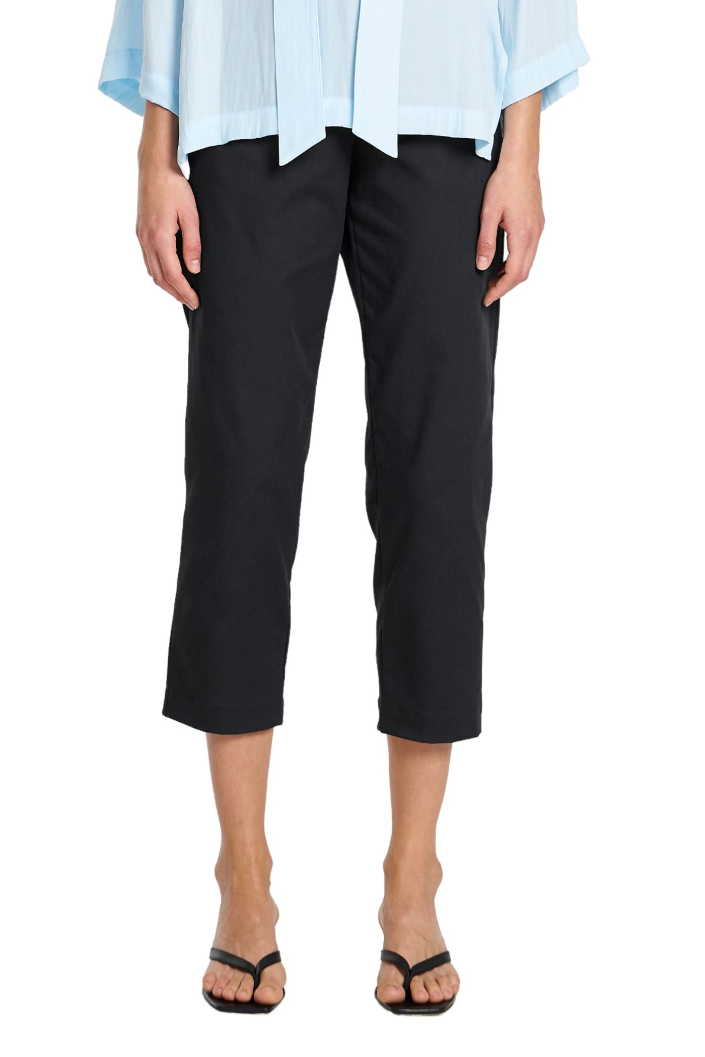 Person wearing black pants and a light blue top on a white background