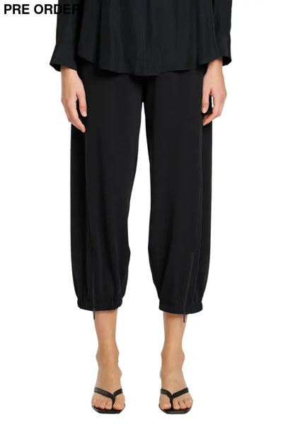 Person wearing a black outfit with wide-leg pants on a white background