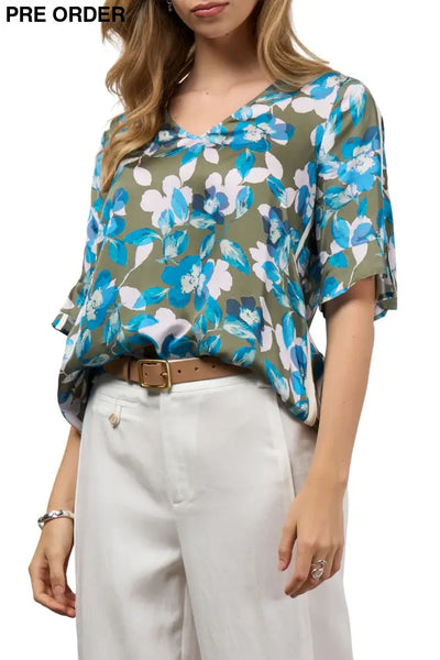 Woman wearing a floral blouse with blue and white flowers on a green background