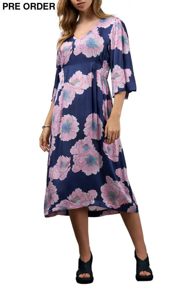Woman wearing a navy blue dress with pink floral pattern on a white background